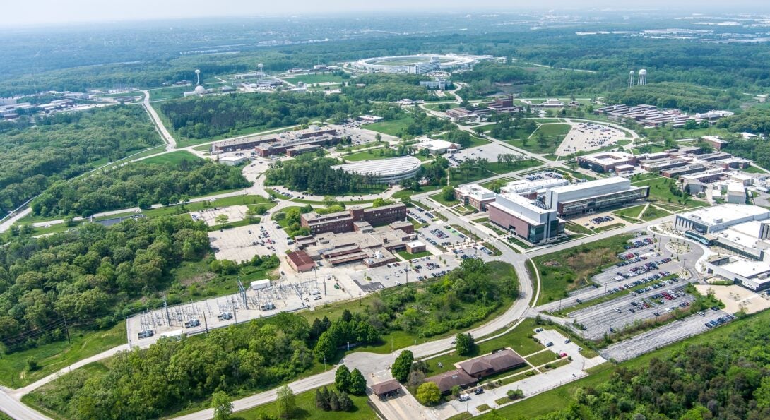 An aerial photo of Argonne National Laboratory, with several buildings connected by roads and surrounded by green trees.