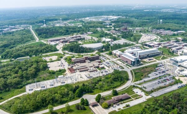 An aerial photo of Argonne National Laboratory, with several buildings connected by roads and surrounded by green trees.